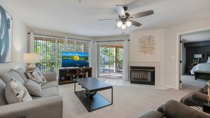 A modern living room with a television, sofa, coffee table, fireplace, and a ceiling fan. - Lakefront living with stunning views and easy pool access, Open-concept space,Close to everything (Lake Ozark)