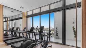 Een moderne sportschool met loopbanden, hometrainers en elliptische machines, grote ramen met uitzicht op de stad, en een schoon, minimalistisch design.