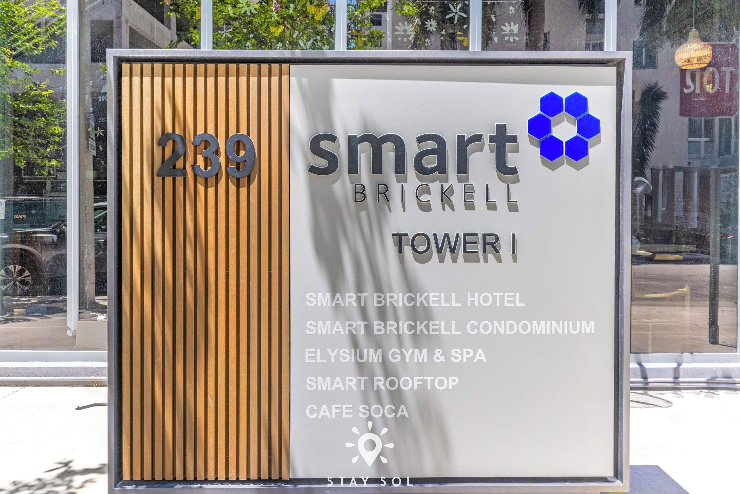 Letrero de Smart Brickell Tower I que enumera servicios como hotel, gimnasio, spa, azotea y cafetería.