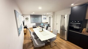 A modern kitchen with a dining area, a refrigerator, and a built-in oven.