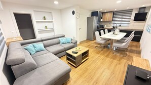 A modern living room with a grey sofa, a coffee table, and a dining area with a white table and chairs.
