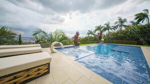 Una piscina con vistas al horizonte de la ciudad, rodeada de palmeras y un cielo nublado.