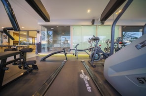 Ein modernes Fitnessstudio mit Trainingsgeräten, großen Fenstern und Blick ins Freie.