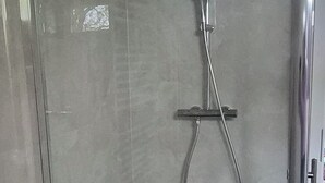 Eine Dusche mit Handbrause, Wandarmatur und Fliesenboden.
