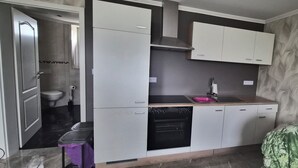 Eine kompakte Küche mit Einbauofen, Spüle und Mikrowelle. Eine Tür führt ins Badezimmer.