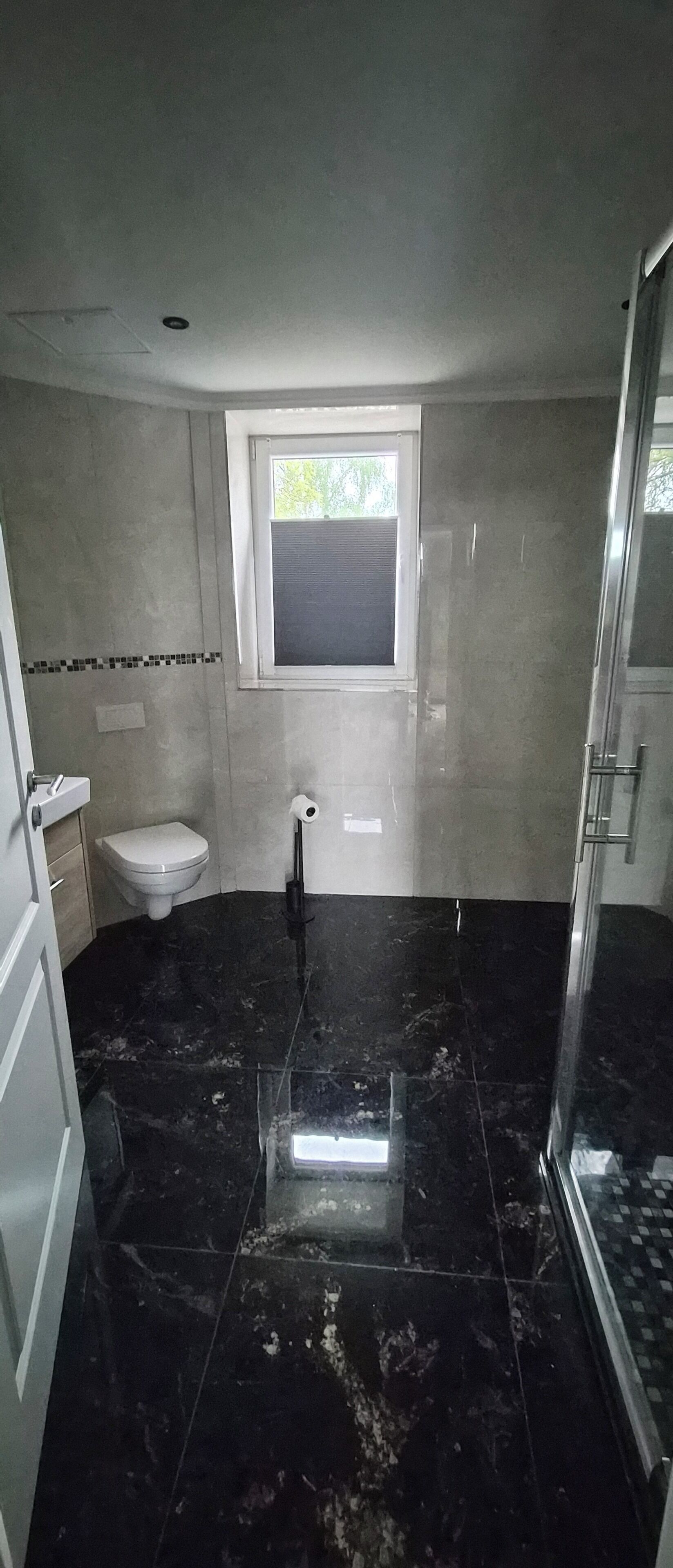 A bathroom with a toilet, a bidet, a window, and a shower area.