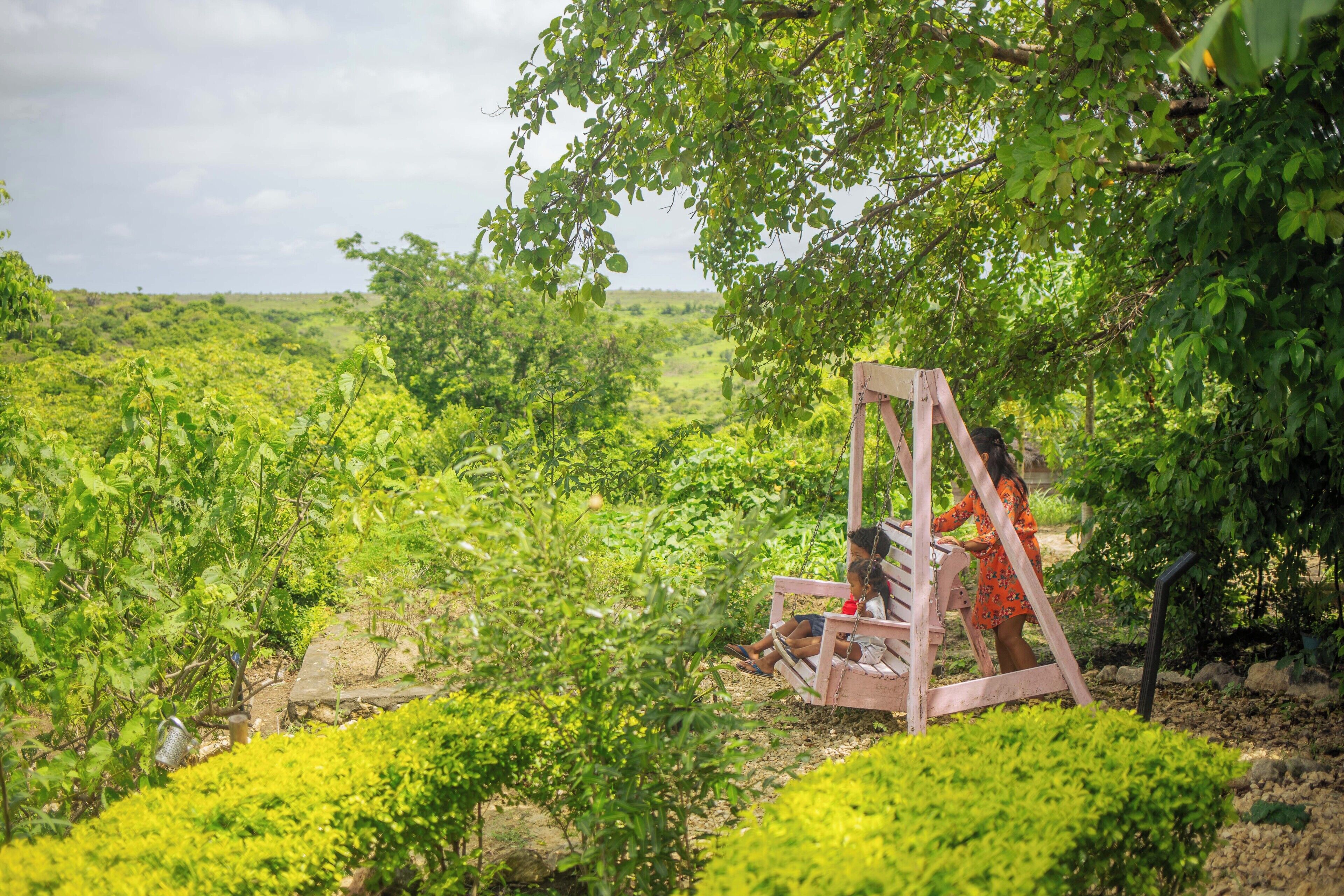 A garden with a swing set and a person sitting on it.