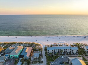 Oversigtsbillede af et kysthotel med flere bygninger, en strand og krystalklart hav.