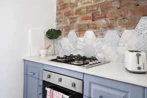 A kitchen with a gas stove, a toaster, and a brick wall backsplash. - OVERSIZED, CONTEMPORARY & CHARMING-GREAT VALUE!3min train to CBD/Shared Parking. (Darlinghurst)