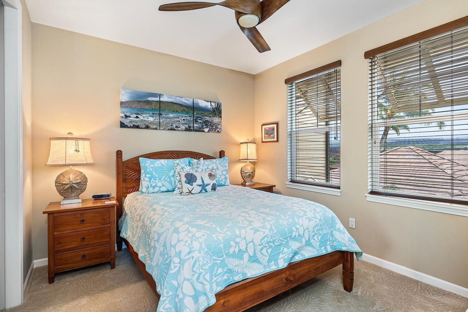 A bedroom with a bed, nightstands, a ceiling fan, a painting, and a window with blinds.