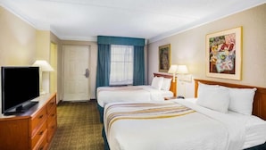 A hotel room with two beds, a television, a desk, and a painting on the wall. - La Vista Express- Formerly La Quinta (Eagle Pass)