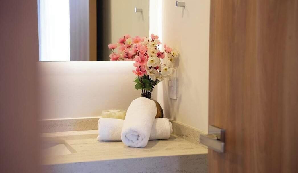 A bathroom with a sink, a towel, and a vase of flowers.