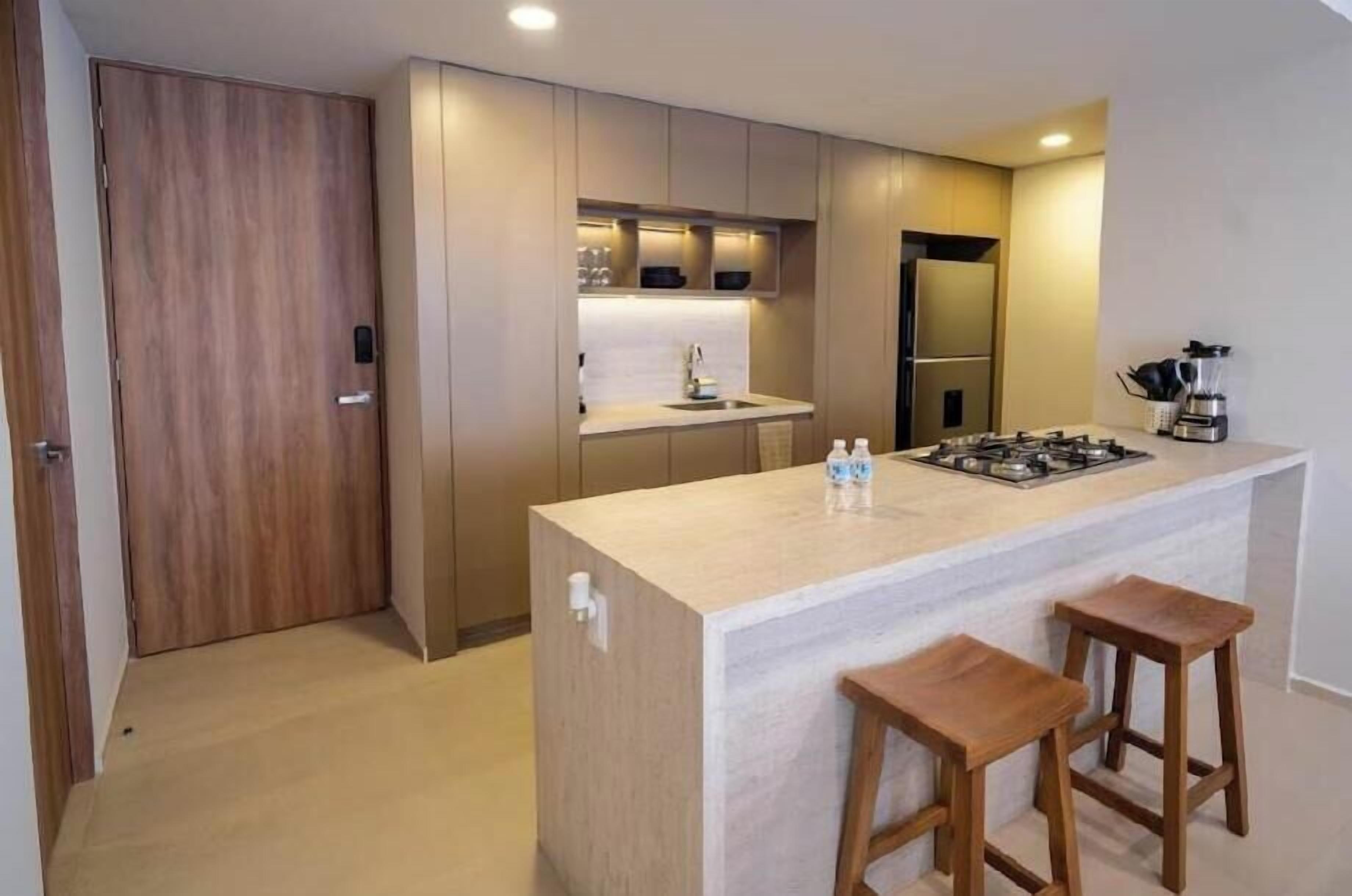 Cozinha moderna com ilha central, banquetas e eletrodomésticos embutidos.
