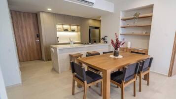 Uma cozinha moderna com eletrodomésticos embutidos, um espaço de refeições com mesa e cadeiras de madeira e uma pequena ilha com pia.