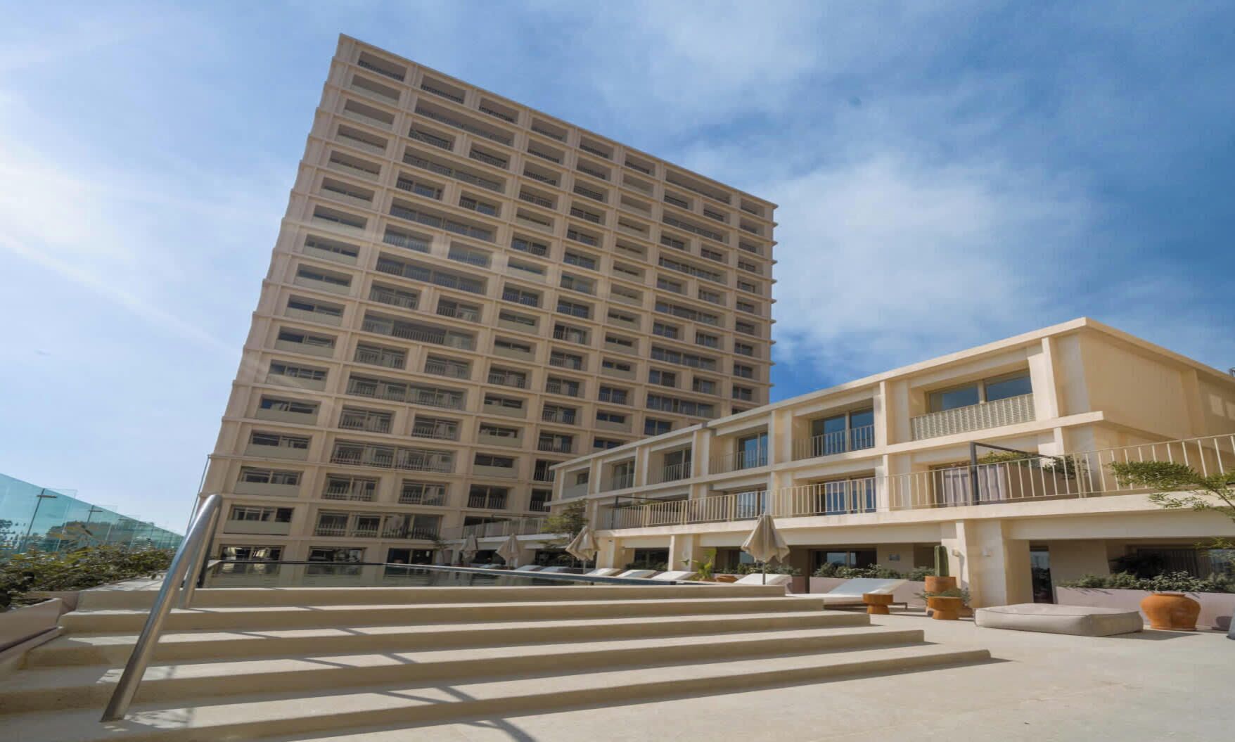 Um hotel com vários andares, pátio central, área de estar ao ar livre e piscina.