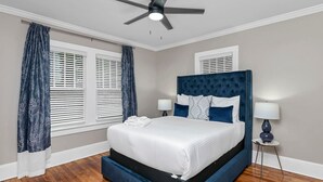 Ein Schlafzimmer mit Bett, Vorhängen, Deckenventilator und Nachttisch.