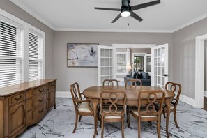 Comedor con mesa y sillas de madera, ventilador de techo y vista a otra habitación.