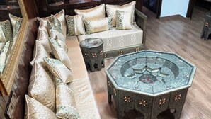 Une pièce comprenant un long canapé, deux poufs et un tapis à motifs.