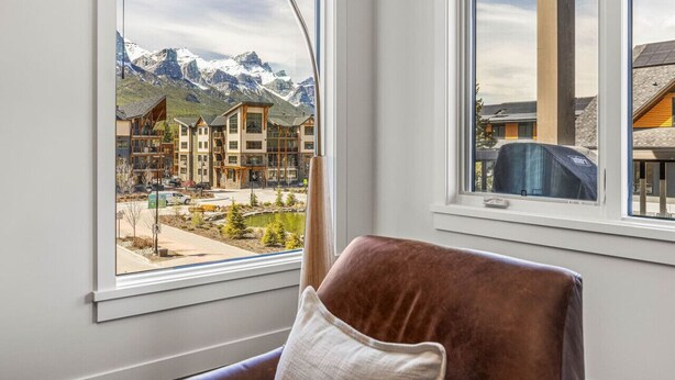 Ein Zimmer mit einem großen Fenster und Blick auf einen Berg und Gebäude.
