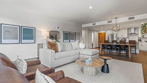 Ein modernes Wohnzimmer mit grauem Sofa, Couchtisch und Essbereich mit Holztisch und Stühlen.