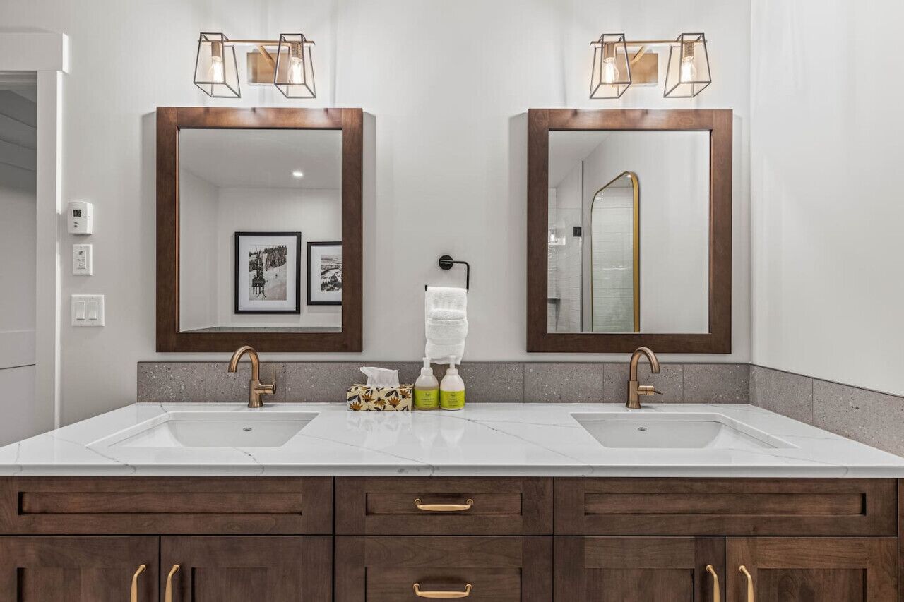 A bathroom with two sinks, wooden cabinets, and a mirror with a towel rack.
