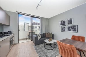 Eine moderne Wohnung mit Küche, Essbereich und einem Balkon mit Blick auf die Stadt.