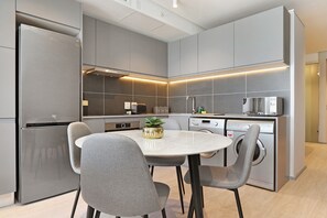 Eine moderne Küche mit grauen Schränken, einem Edelstahlkühlschrank, einem eingebauten Backofen, einer Mikrowelle und einem Geschirrspüler.