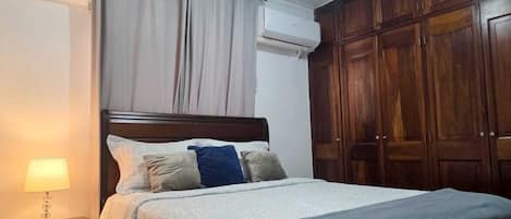 Une chambre à coucher avec un lit, une table de chevet et une armoire.