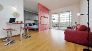 Uma sala de estar moderna com um sofá vermelho, um sofá cinza e uma área de jantar em vermelho e cinza.