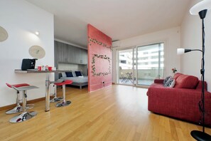 Ein modernes Wohnzimmer mit einem roten Sofa, einem grauen Sofa und einer rot-grauen Essecke.