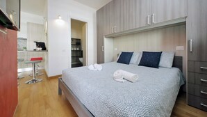 Quarto com cama, duas almofadas, mesa de cabeceira e guarda-roupa.
