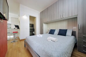 Ein Schlafzimmer mit einem Bett, zwei Kissen, einem Nachttisch und einem Kleiderschrank.