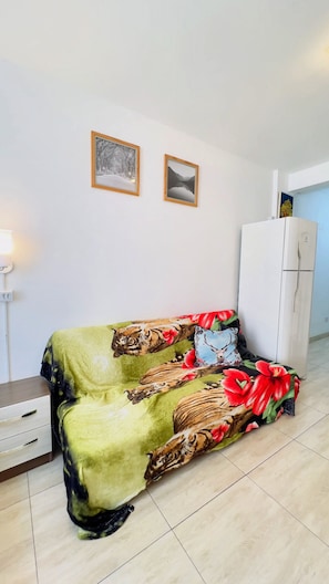 Una habitación con un sofá estampado con motivos de tigre y flores, un aparador blanco y dos cuadros en la pared.