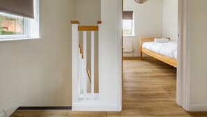 A room with a wooden bed, a radiator, and a window. - Swift Host | Watermeadow | Sleeps 5 | Parking | Garden | Dereham (488234) (Elsing)