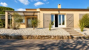 Una casa moderna con fachada de piedra, ventanas amplias y un camino de piedra que lleva a la entrada.