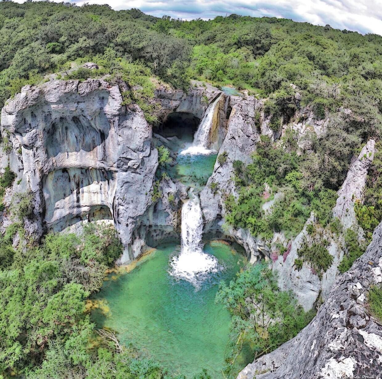 Formazione rocciosa naturale con una cascata e acqua cristallina alla base.