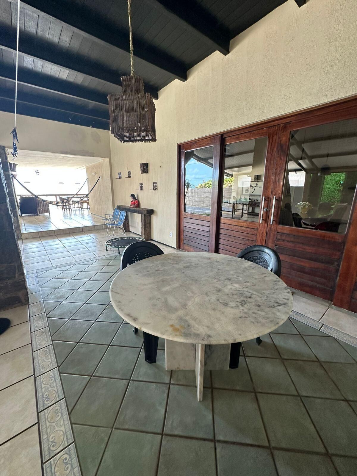 A covered outdoor patio with a round table, chairs, and a hanging light fixture.
