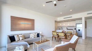 Ein modernes Wohnzimmer mit einer Couch, einem Couchtisch, Korbstühlen und einem Deckenventilator.