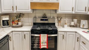 A kitchen with white cabinets, a black stove, and a wooden countertop.