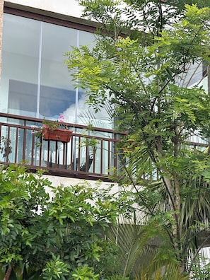 Ein Balkon mit Holzgeländer, einem Blumentopf und einem Fenster mit Blick auf ein Gebäude.