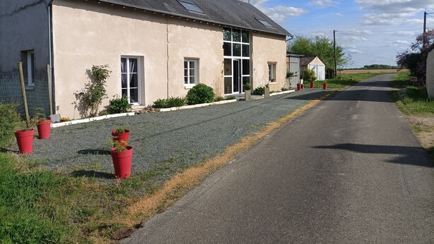 A two-story building with a sloped roof, large windows, and a gravel driveway. - For a long weekend or a vacation in the countryside. (Thilouze)