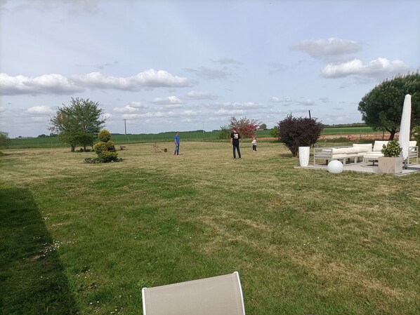 Een buitenruimte met een gazon, zitgedeelte en enkele bomen.