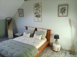 A bedroom with a bed, pillows, a bedside lamp, and wall art.