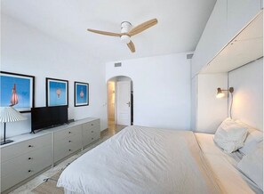 A bedroom with a bed, a ceiling fan, a TV on a dresser, and framed pictures on the wall. - Mb.b53 - Beachfront Penthouse With Sea Views (Estepona)