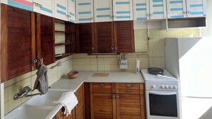 A kitchen with wooden cabinets, a white stove, and a sink.
