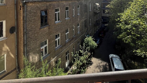 A multi-story building with a brick facade, multiple windows, and a visible balcony.