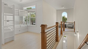 Ein geräumiges Zimmer mit einem Etagenbett, einer Holztreppe und Blick ins Freie.