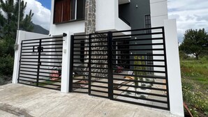 Une maison moderne à deux étages, dotée d’une entrée sécurisée par un portail, d’une cheminée en pierre et d’un garage.