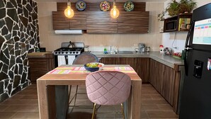Une cuisine moderne dotée d’un îlot central, de luminaires suspendus et d’un réfrigérateur.
