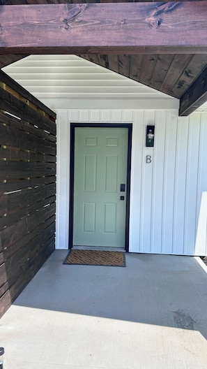 A single-story building with a green door, a mailbox, and a doormat. - Patchwork Paradise B - New 2BR Home 3 Blocks from Missouri Star (Hamilton)